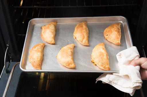 Bring out and cool down empanadas in the oven