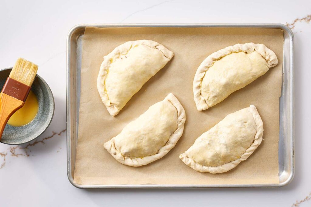 Place the empanadas on a baking sheet, and brush them with the beaten egg